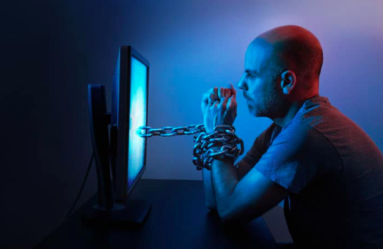 Pornography Addiction: man chained around wrists through computer screen.